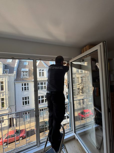 Handwerker montiert Katzennetz an Montagestütze für sichere, bohrfreie Installation
